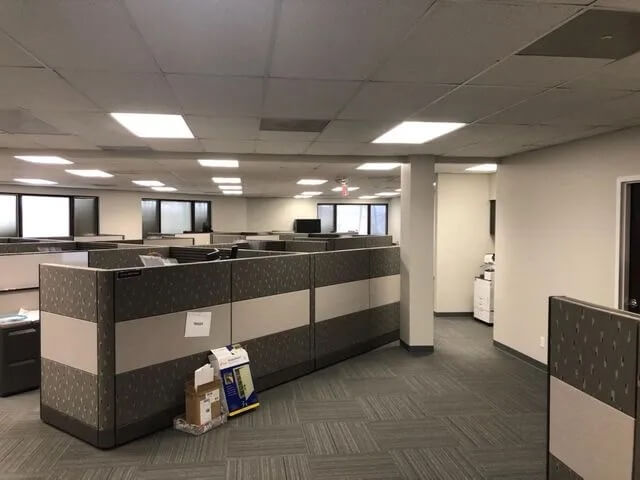 Empty office with cubicles and boxes on floor.
